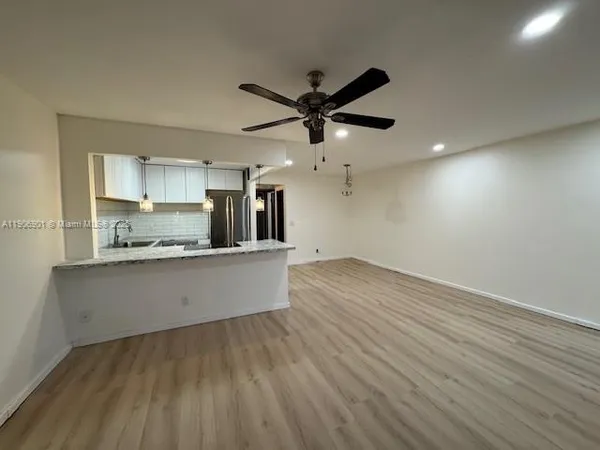 a large kitchen with stainless steel appliances a large counter top a sink a refrigerator and a stove