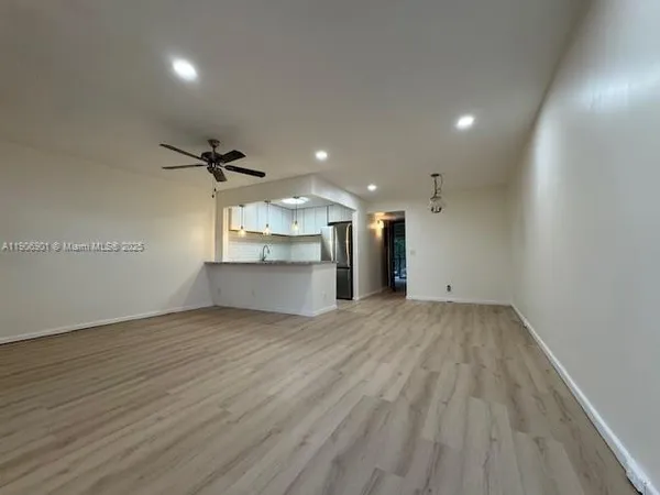 an empty room with wooden floor sink and windows