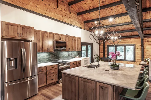 a kitchen with stainless steel appliances granite countertop a refrigerator a sink dishwasher a stove and a refrigerator