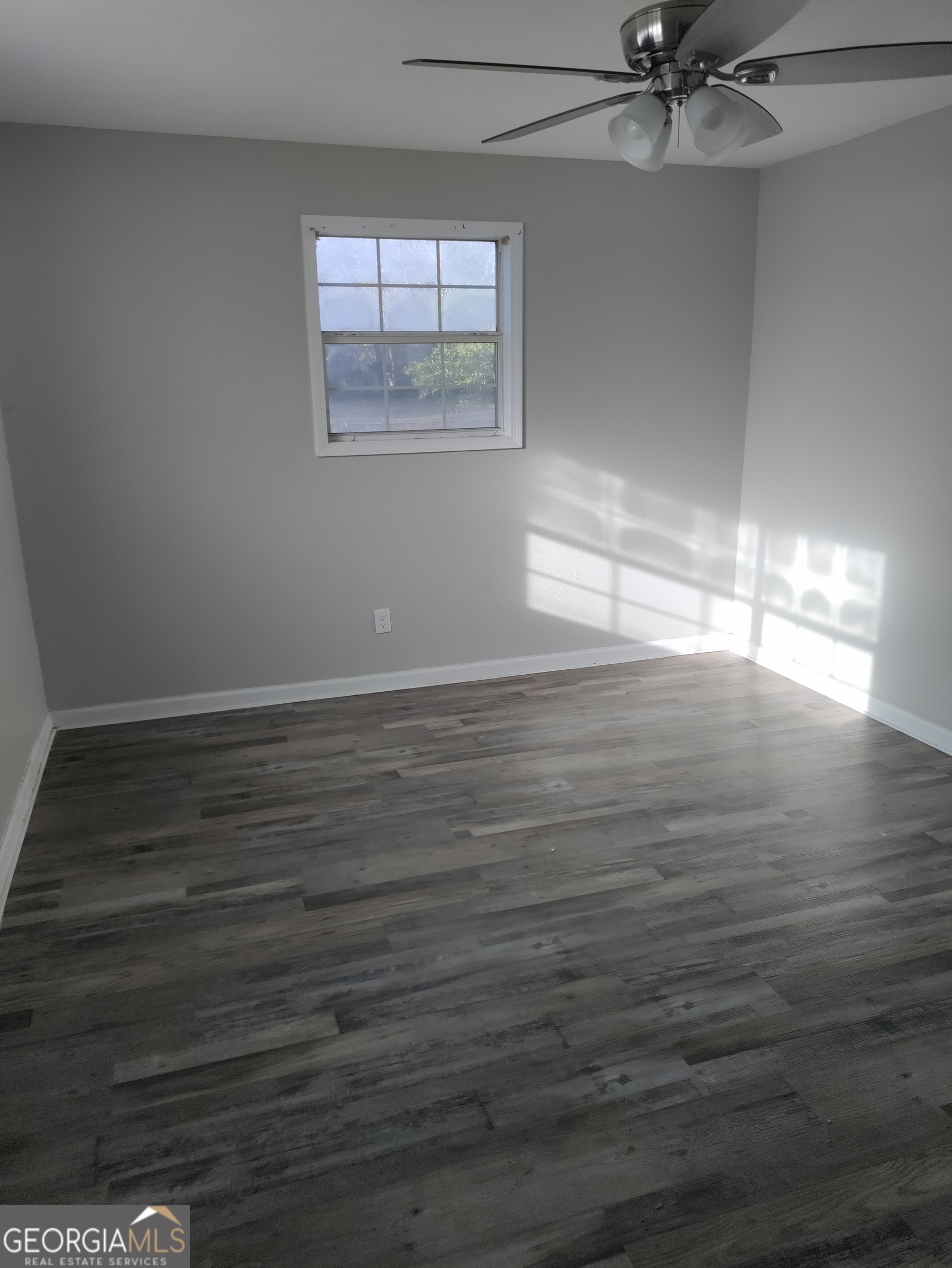 164 Davis Street Southeast Camilla, GA 31730 - Photo 4 of 10 an empty room with wooden floor fan and windows