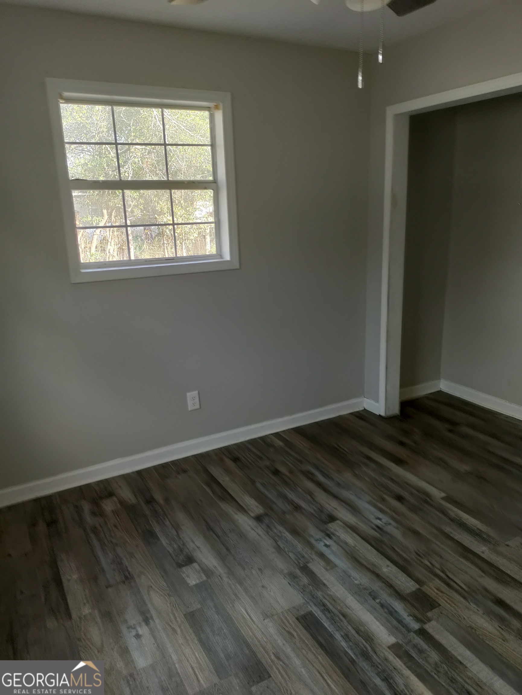 164 Davis Street Southeast Camilla, GA 31730 - Photo 5 of 10 an empty room with wooden floor and windows