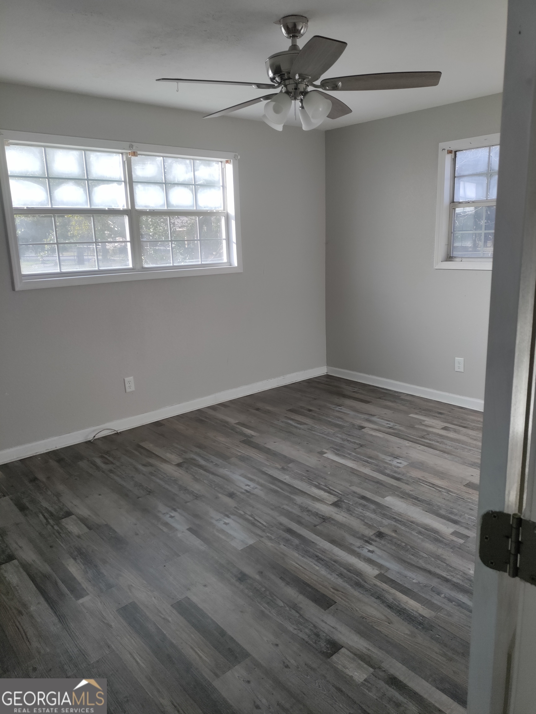 164 Davis Street Southeast Camilla, GA 31730 - Photo 6 of 10 an empty room with wooden floor fan and windows