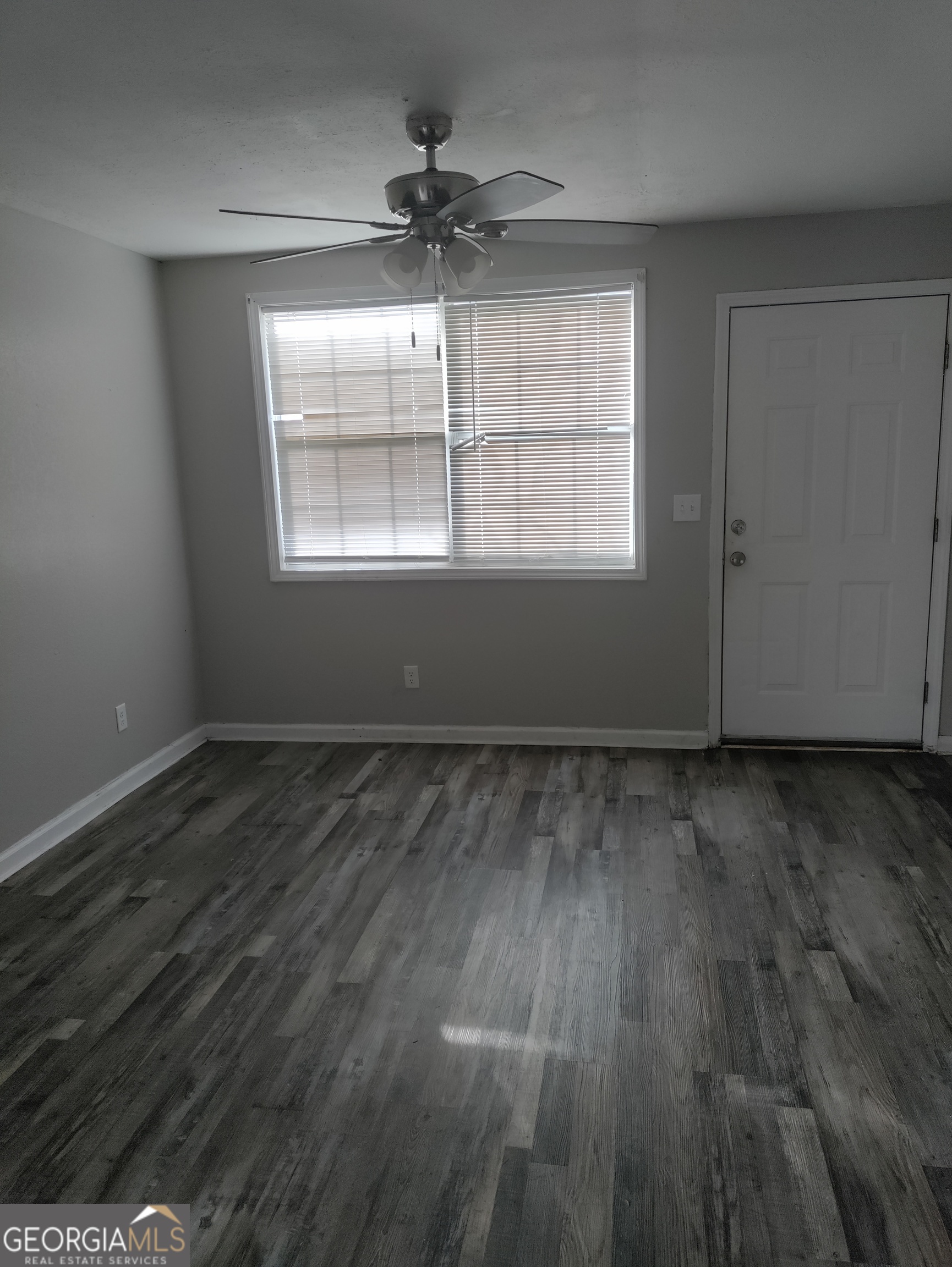 164 Davis Street Southeast Camilla, GA 31730 - Photo 8 of 10 an empty room with wooden floor chandelier fan and windows
