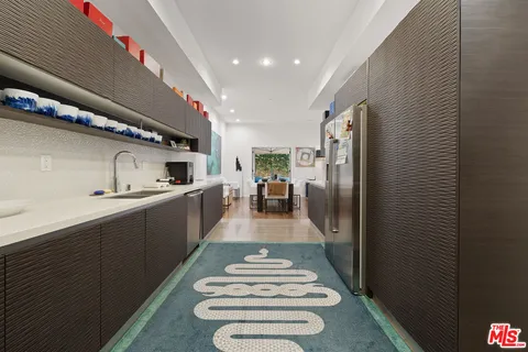 a kitchen with stainless steel appliances granite countertop a refrigerator a sink dishwasher a stove and white countertops with wooden floor