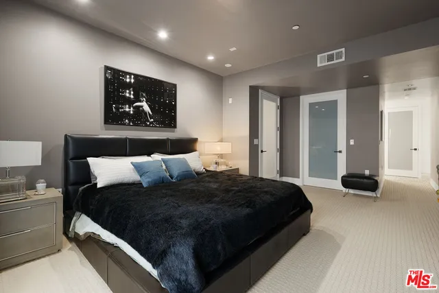 a large bed in a white room with painting on the wall