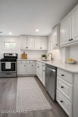 a kitchen with granite countertop a sink cabinets stainless steel appliances and a window