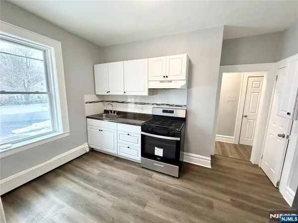a kitchen with stainless steel appliances white cabinets and wooden floors