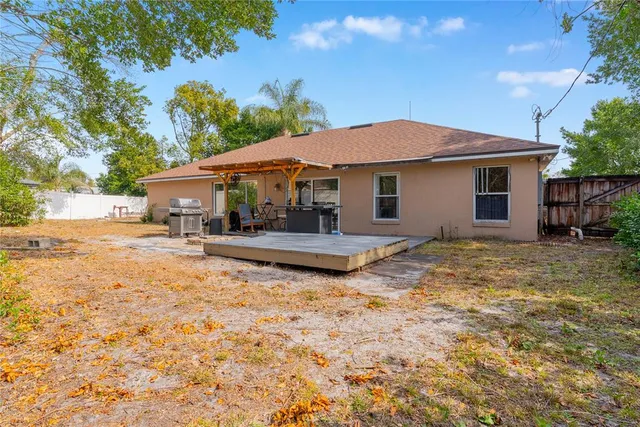 a backyard of a house with table and chairs under an umbrella
