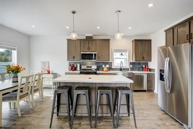 a kitchen with stainless steel appliances kitchen island granite countertop a dining table chairs stove and refrigerator