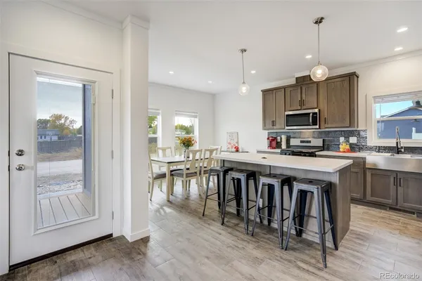 a kitchen with kitchen island granite countertop a stove a sink a dining table and chairs