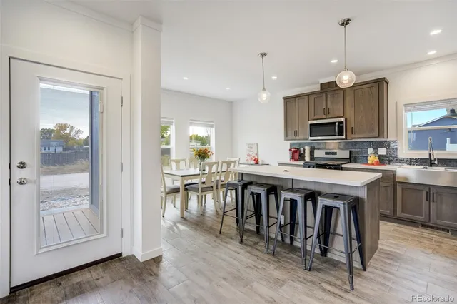a kitchen with kitchen island granite countertop a stove a sink a dining table and chairs
