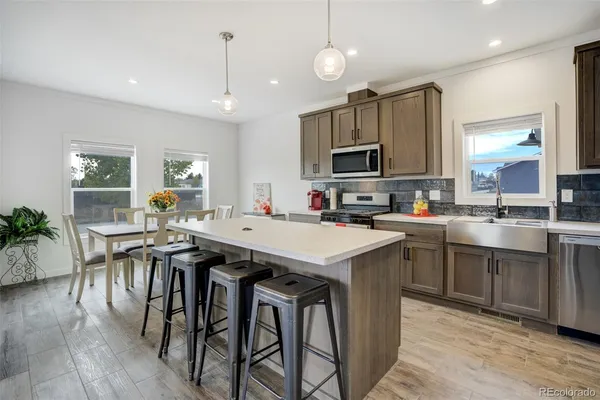 a kitchen with stainless steel appliances granite countertop a stove a sink a microwave a center island and furniture