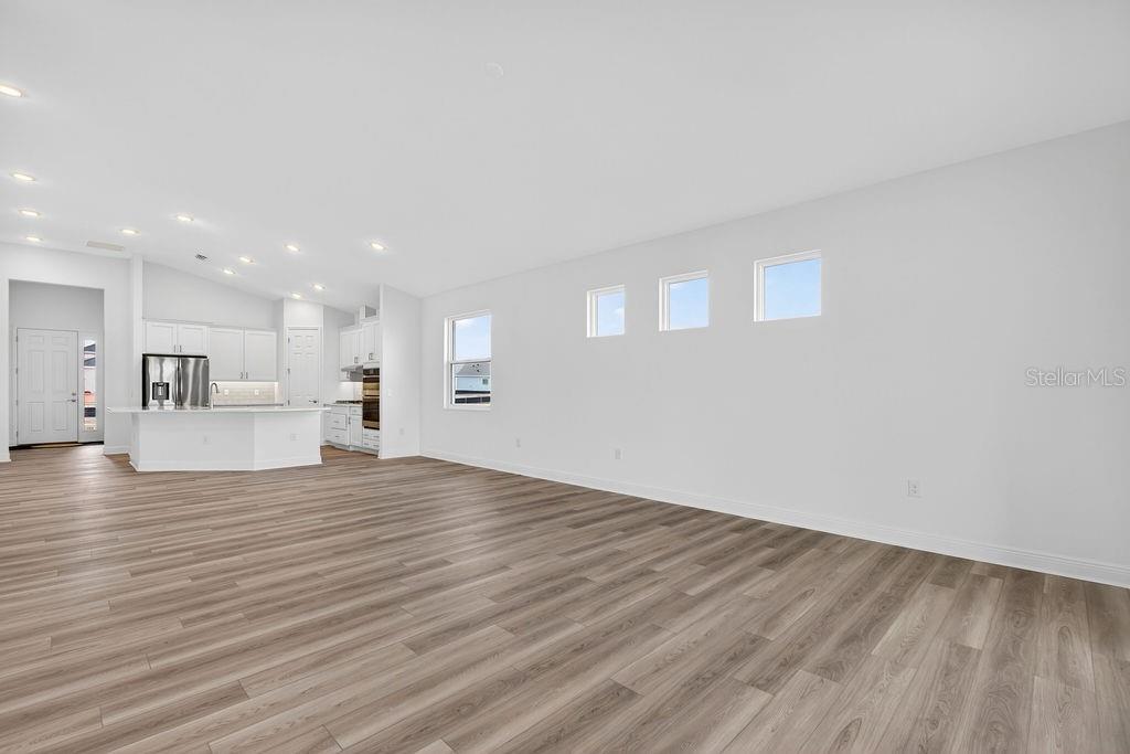 3951 Kennebunk Loop Mount Dora, FL 32757 - Photo 12 of 51 a view of an empty room with wooden floor and a kitchen