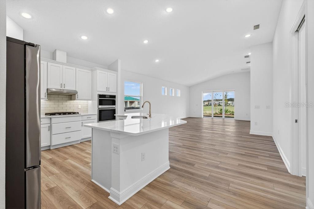 3951 Kennebunk Loop Mount Dora, FL 32757 - Photo 7 of 51 a kitchen with kitchen island white cabinets and stainless steel appliances
