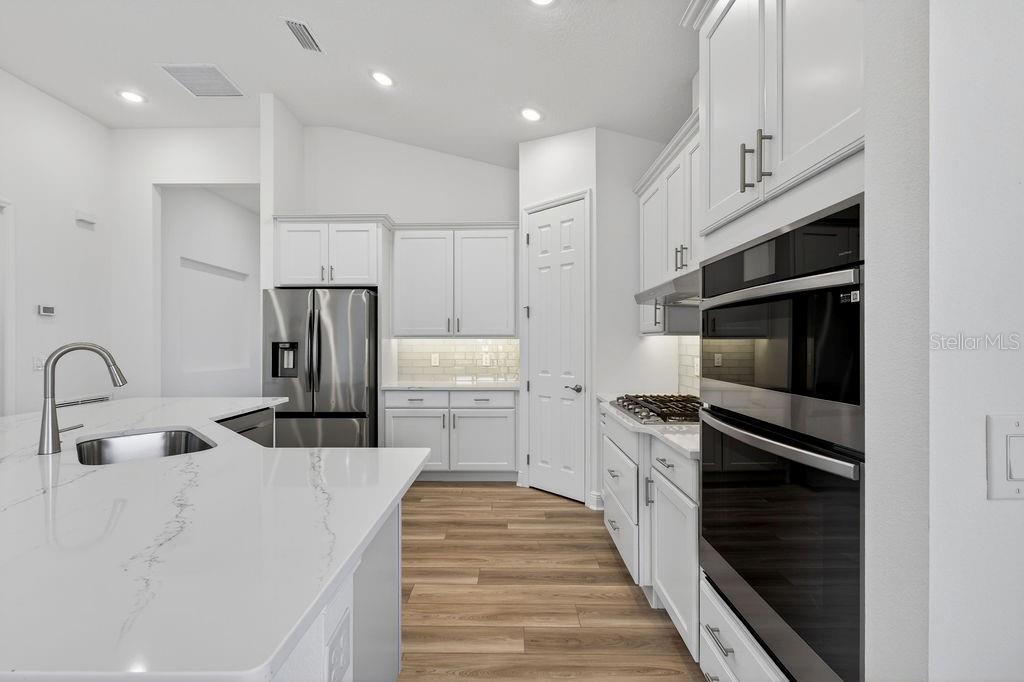 3951 Kennebunk Loop Mount Dora, FL 32757 - Photo 8 of 51 a kitchen with white cabinets and stainless steel appliances