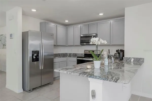 a kitchen with stainless steel appliances granite countertop a refrigerator a stove and a sink