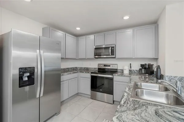 a kitchen with granite countertop a refrigerator sink and stove