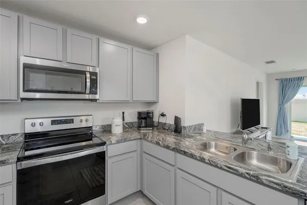 a kitchen with granite countertop a sink and steel appliances