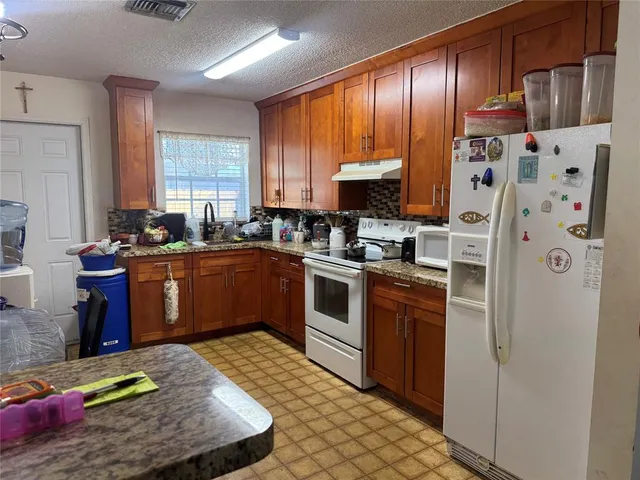 a kitchen with stainless steel appliances granite countertop a refrigerator a sink dishwasher a stove with wooden cabinets