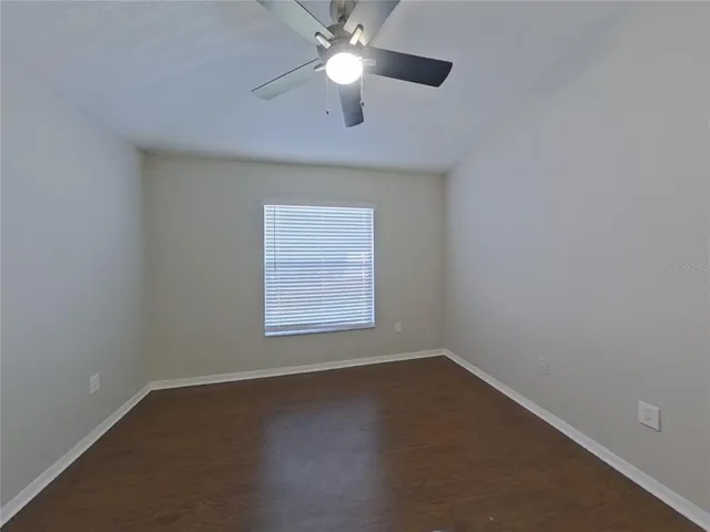 an empty room with a window and a ceiling fan