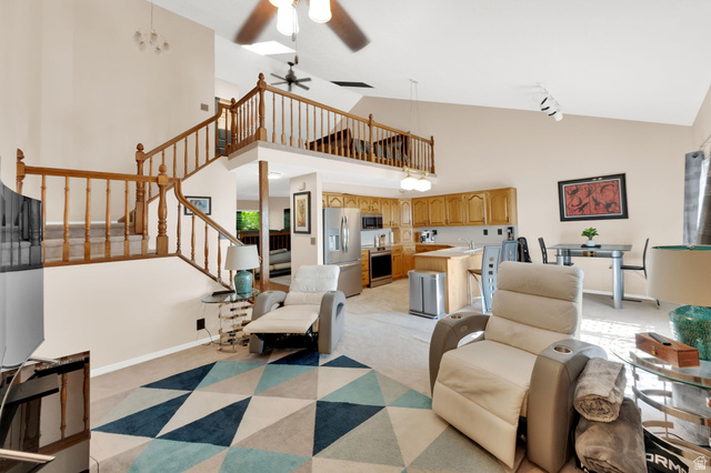 5057 South Ridgedale Drive Ogden, UT 84403 - Photo 23 of 69 Open-concept living space featuring vaulted ceilings, a prominent wooden staircase with balusters, and a kitchen with wood cabinetry and an island breakfast bar