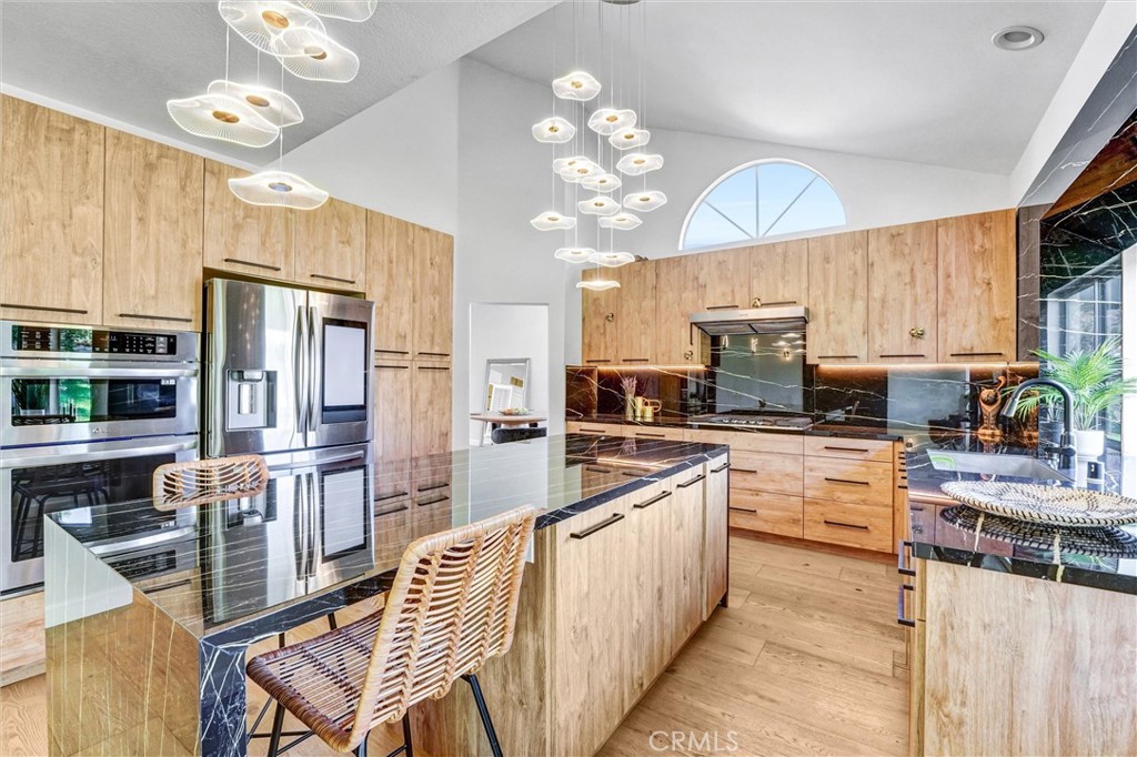 22411 Holly Court Saugus, CA 91390 - Photo 1 of 42 a kitchen with stainless steel appliances granite countertop a refrigerator a sink dishwasher a dining table and chairs with wooden floor