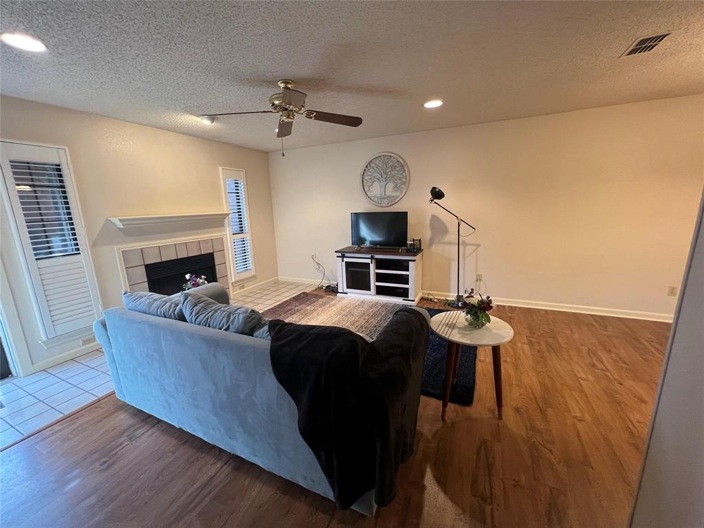 3129 Sappington Place Fort Worth, TX 76116 - Photo 3 of 15 Living room featuring a textured ceiling, a tile fireplace, recessed lighting, wood finished floors, and a ceiling fan