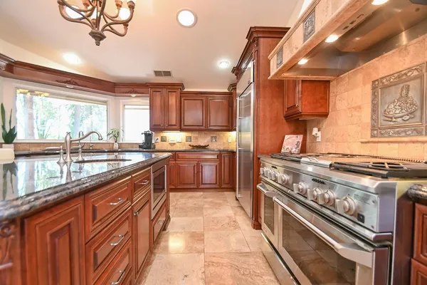 a kitchen with stainless steel appliances granite countertop a stove a sink dishwasher and a refrigerator