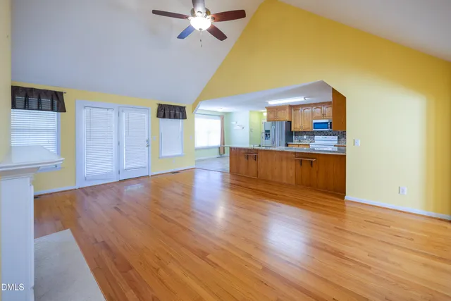 a view of a livingroom with wooden floor and a kitchen