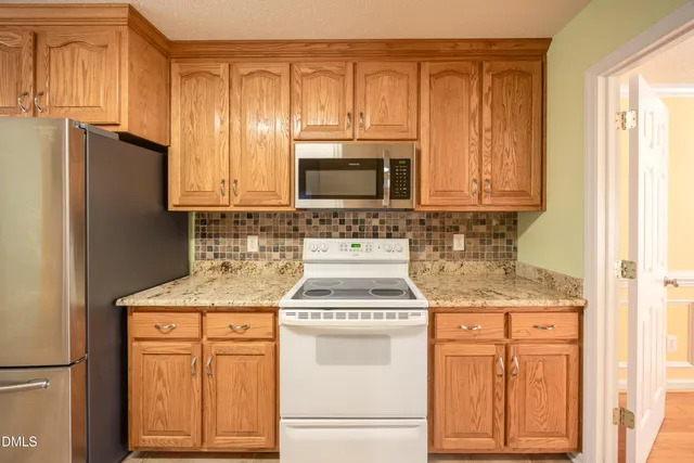 a kitchen with stainless steel appliances granite countertop a sink stove refrigerator and cabinets