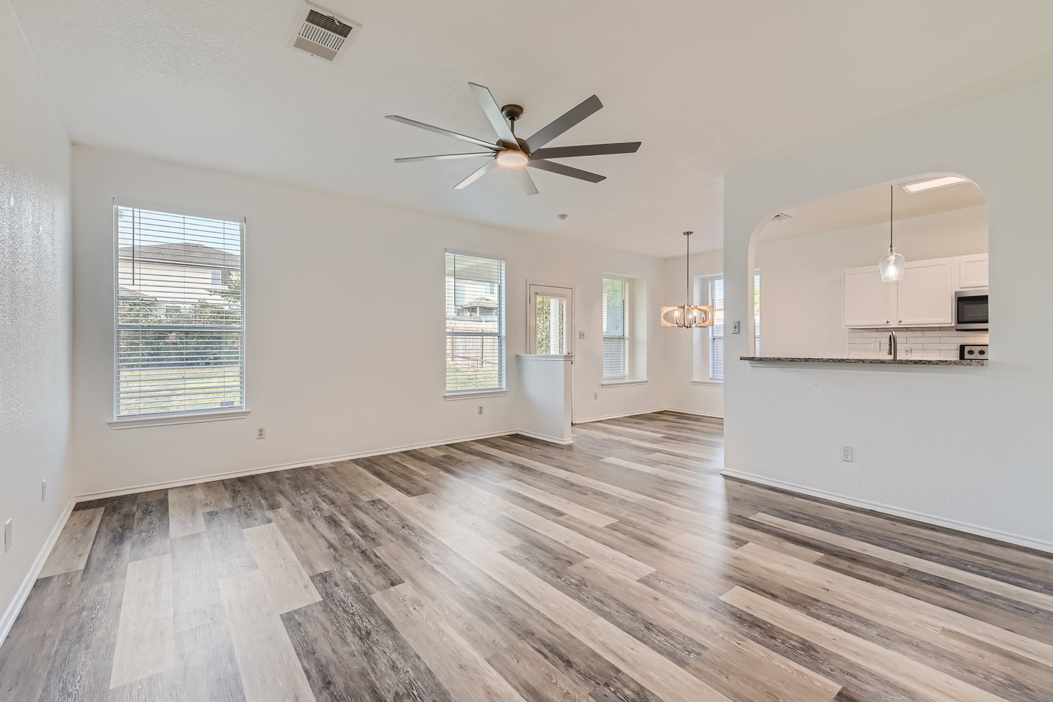 115 Killian Loop Hutto, TX 78634 - Photo 14 of 14 A well-lit interior features stylish plank flooring, an open floor plan, and a kitchen pass-through.