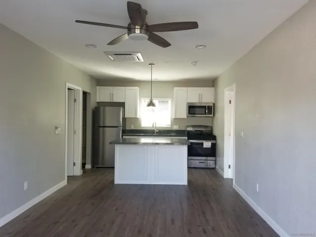 a kitchen with stainless steel appliances granite countertop a refrigerator a sink dishwasher a stove and white countertops with wooden floor