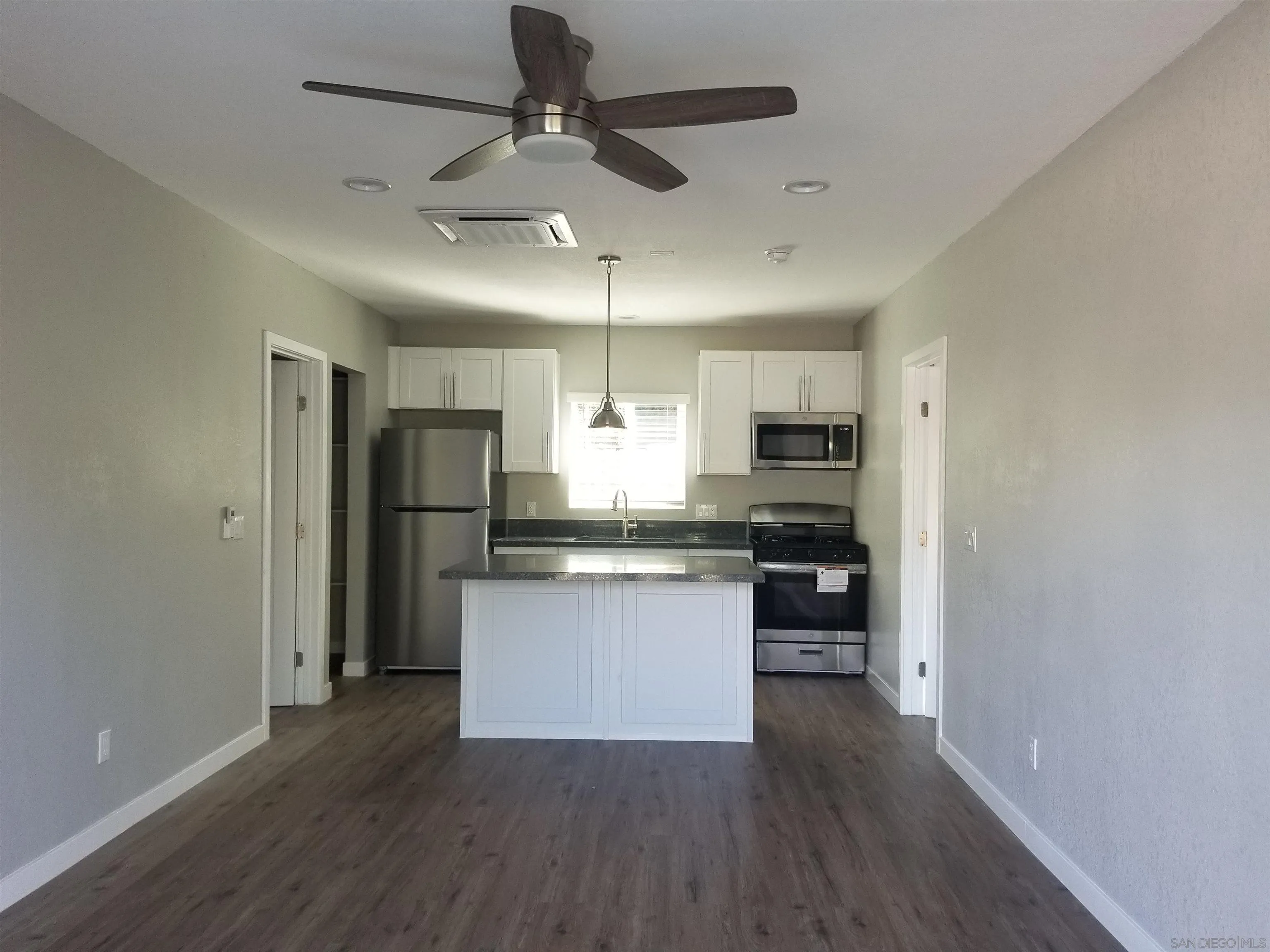 5051 63rd Street San Diego, CA 92115 - Photo 17 of 28 a kitchen with stainless steel appliances granite countertop a refrigerator a sink dishwasher a stove and white countertops with wooden floor