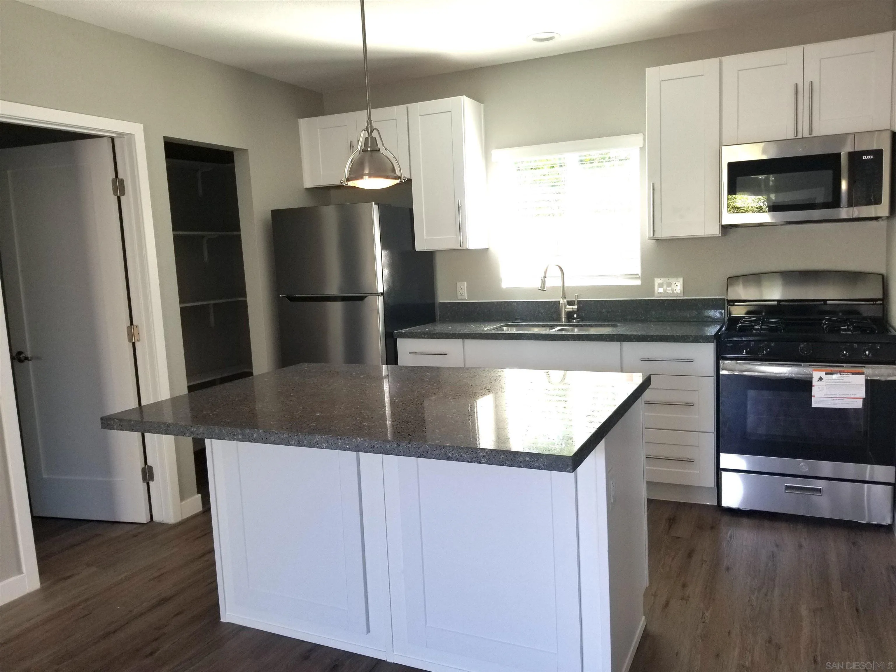 5051 63rd Street San Diego, CA 92115 - Photo 18 of 28 a kitchen with granite countertop a refrigerator a sink a stove and microwave