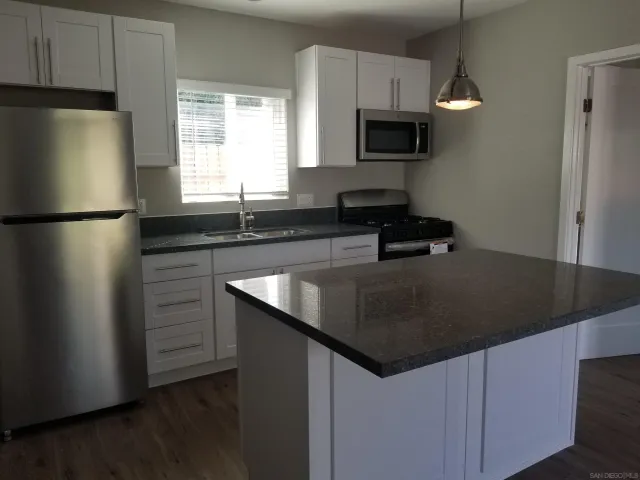 a kitchen with granite countertop a refrigerator and a sink