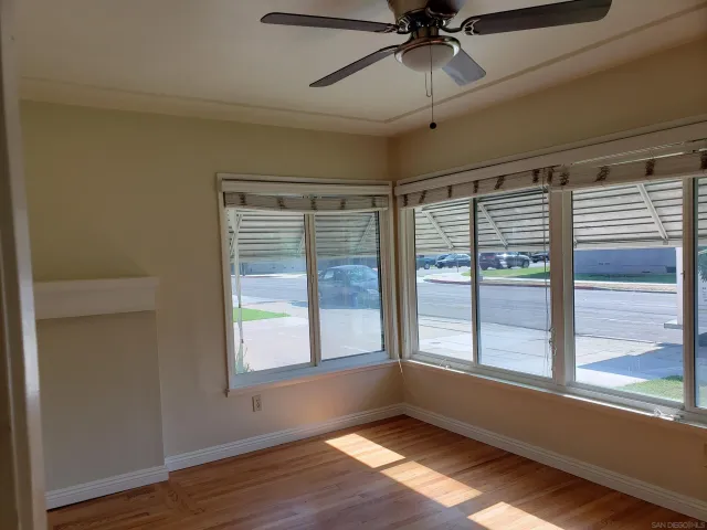 a view of an empty room with a window and wooden floor