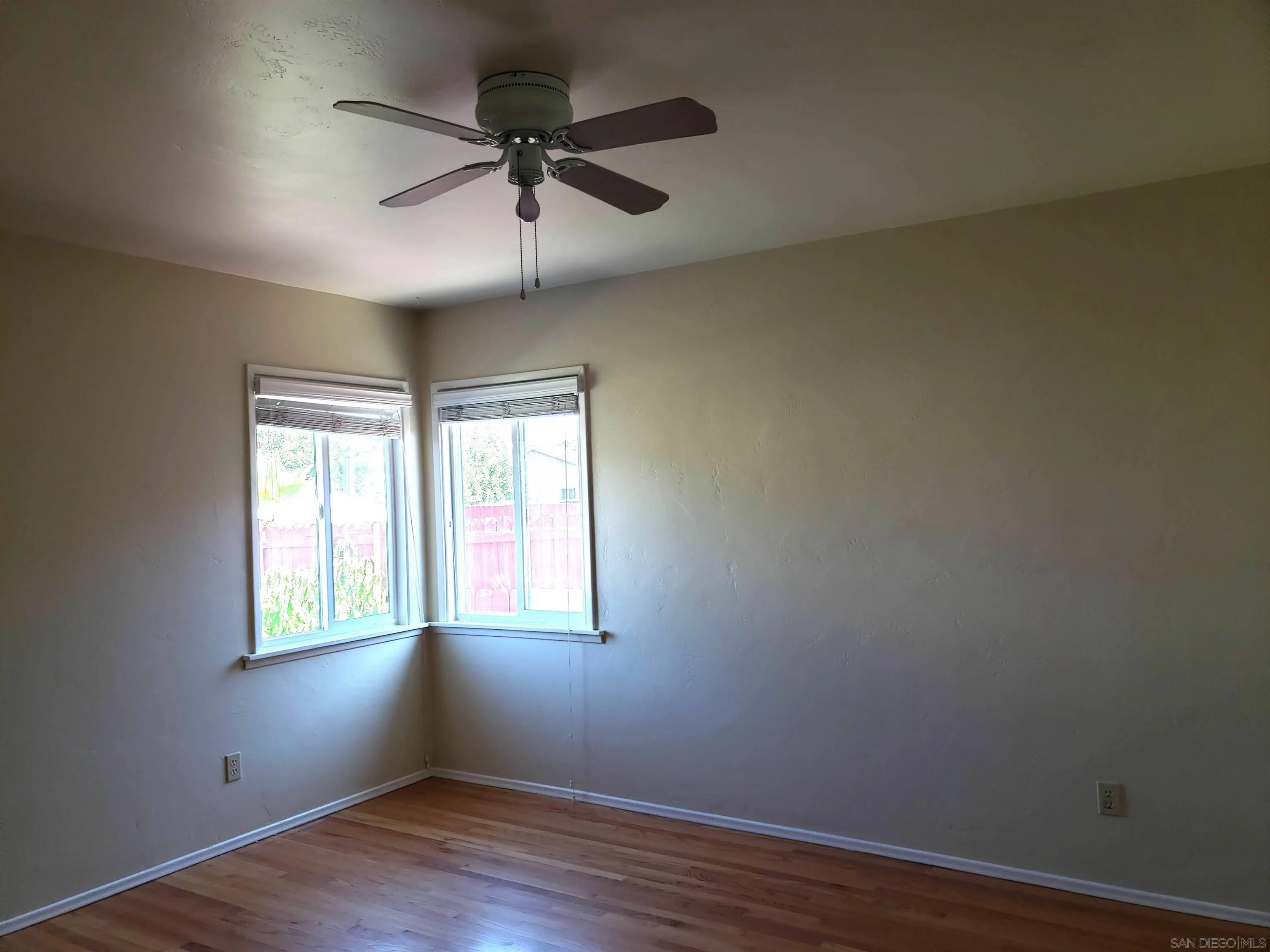 5051 63rd Street San Diego, CA 92115 - Photo 8 of 28 an empty room with wooden floor ceiling fan and windows
