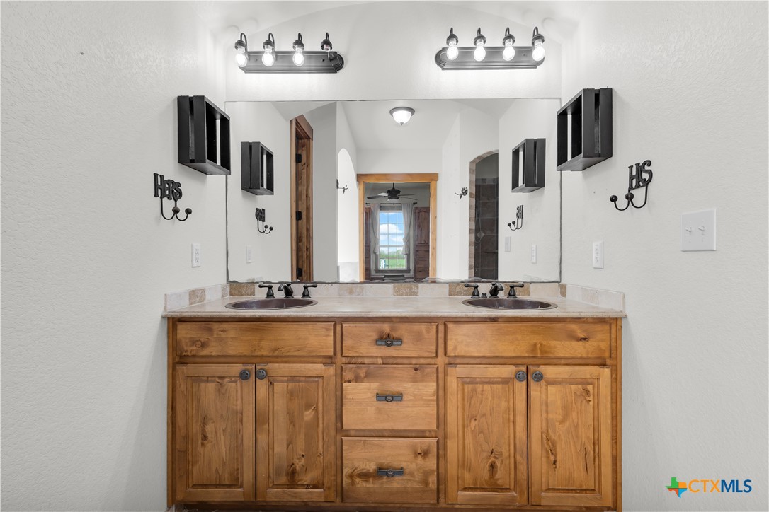 12491 Madison Lane Justin, TX 76247 - Photo 22 of 38 a bathroom with a granite countertop sink a mirror and cabinets