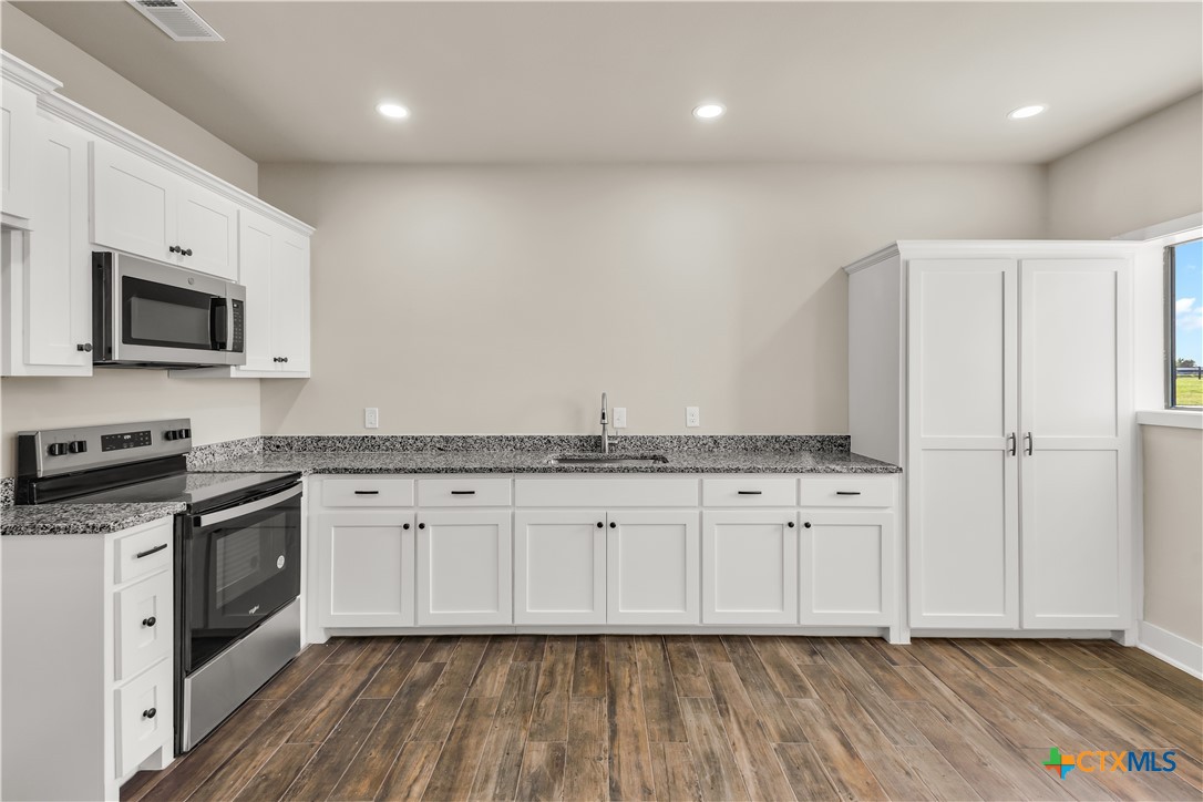 12491 Madison Lane Justin, TX 76247 - Photo 35 of 38 a kitchen with stainless steel appliances granite countertop a stove a sink and a microwave