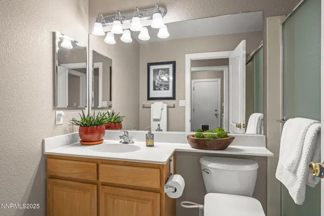a bathroom with a granite countertop toilet sink and mirror