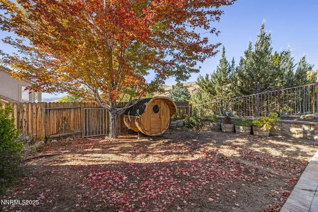 a view of a backyard with large trees and wooden fence
