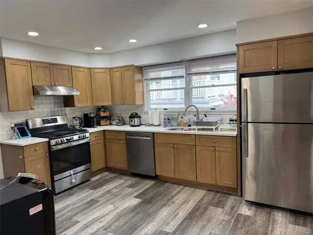 a kitchen with a refrigerator a stove a sink cabinets and wooden floor