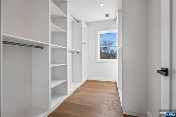 a view of hallway with wooden floor and closet