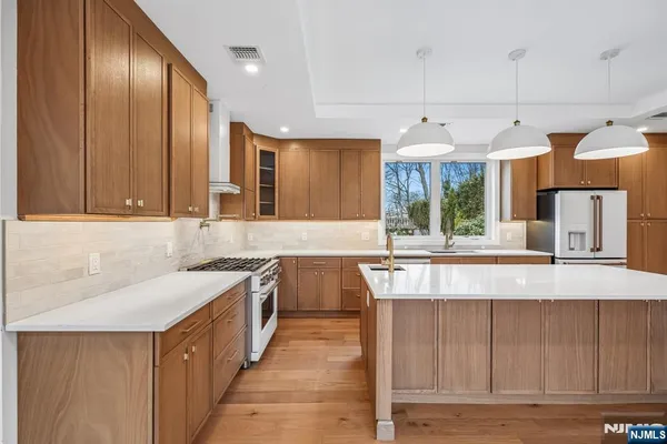 a view of a kitchen with kitchen island granite countertop wooden cabinets and a sink