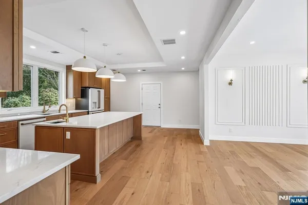 a large kitchen with stainless steel appliances granite countertop a large counter top a sink and a refrigerator