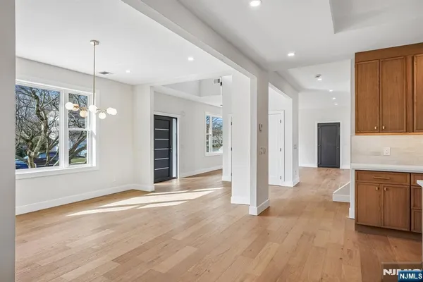 a view of an empty room with wooden floor and a kitchen