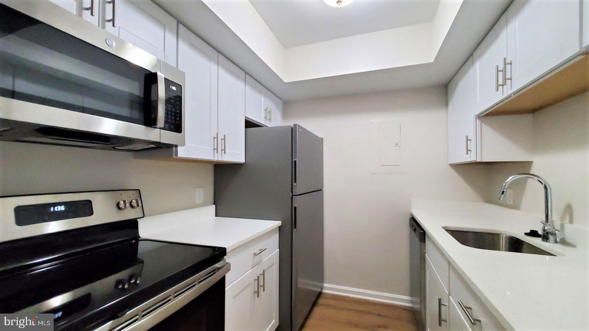 18308 Streamside Drive, Unit 101 Gaithersburg, MD 20879 - Photo 2 of 20 a kitchen with stainless steel appliances a microwave a sink and cabinets