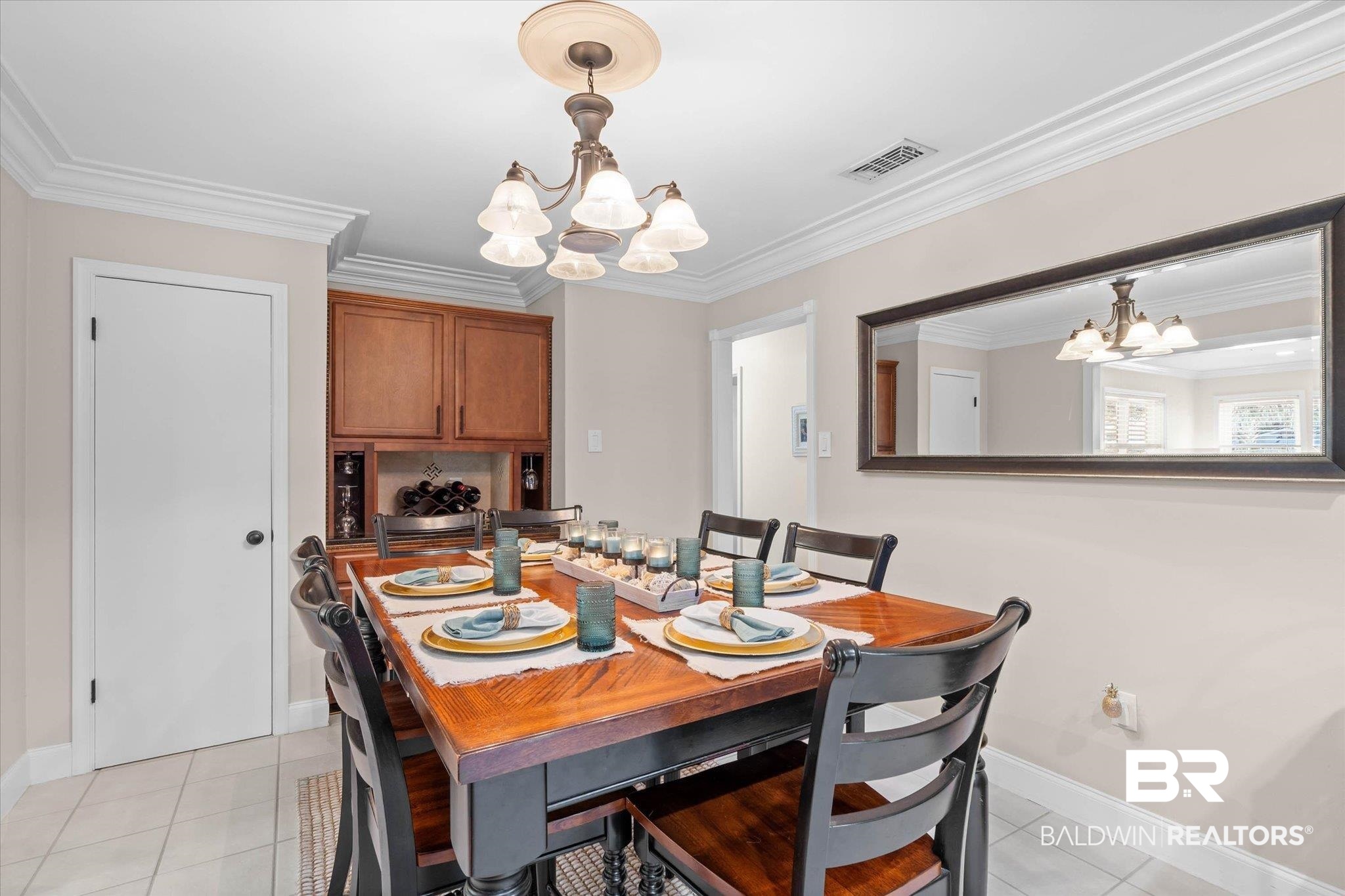 101 Ann Street Daphne, AL 36527 - Photo 13 of 38 Dining area featuring crown molding, a built-in wood-finish cabinet with a wine rack, and tile flooring