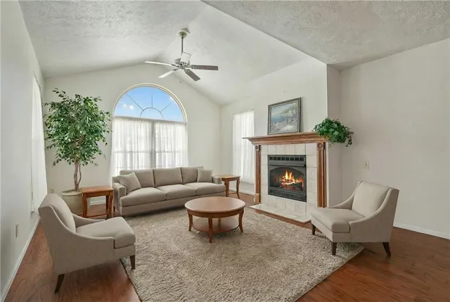 a view of an empty room with wooden floor fireplace and a window