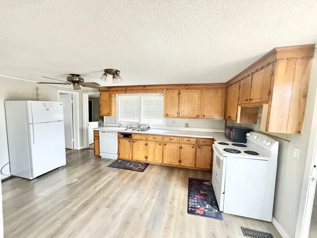 a kitchen with a refrigerator wooden floor and white cabinets
